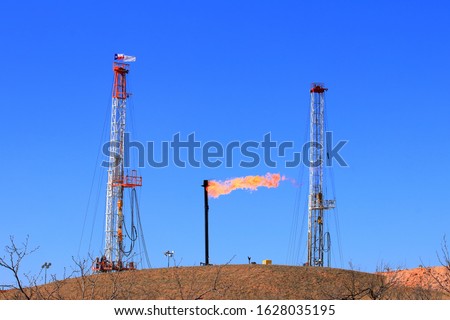 Gas flare between two drilling rigs in the West Texas oil field