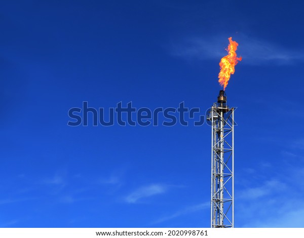 Gas flare is releasing and burning to the\
atmosphere at an offshore gas platform with sky. Fire on a stack of\
flare at oil and gas central processing platform. A gas flare at an\
oil refinery.	