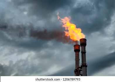 Gas flare stacks against a cloudy background