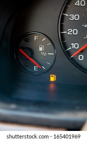 A Gas Guage In A Car Reads Empty And Shows The Warning Light To Let The Driver Know They Are Out Of Gas And Need To Refuel.