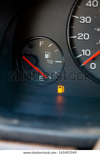 A\
gas guage in a car reads empty and shows the warning light to let\
the driver know they are out of gas and need to\
refuel.