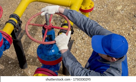 Gas Industry, Gas Transmission System And Gas Pipeline. Communications, The Worker Opens, Closes The Shut-off Valves At The Gas Pumping Station. Part Of The Photo Is Blurry.