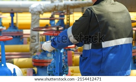 Gas industry, gas transmission system and gas pipeline. Communications, a worker opens and closes shut-off valves at a gas pumping station. Selective focus.