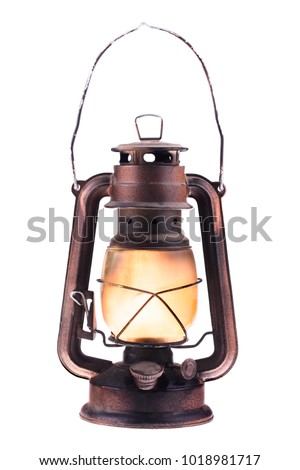 Gas lantern with burning light, isolated on a white background. An antique vintage lamp. Hipster accessory. Camping light. Interior decoration. Rusty, covered with patina. Wire handle
