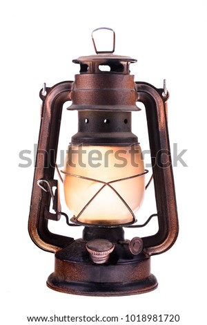 Gas lantern with burning light, isolated on a white background. An antique vintage lamp. Hipster accessory. Camping light. Interior decoration.  Rusty, covered with patina. Metal case, smoked frosted 