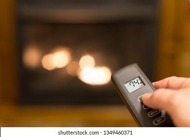 Gas Log Fireplace Being Turned On With A Remote Control That Shows The Temperature Of The Room.