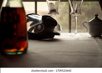 A Gas Mask And Two Wine Glasses Rest Side By Side On A Dining Room Table.