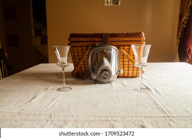 A Gas Mask And Two Wine Glasses Rest Side By Side On A Dining Room Table.