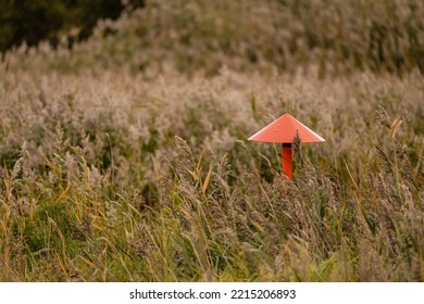 Gas Pipeline Marker In Tall Grass On A Field.