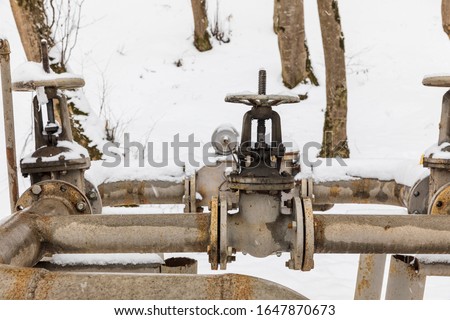 Gas pipes and valves in a snowy forest