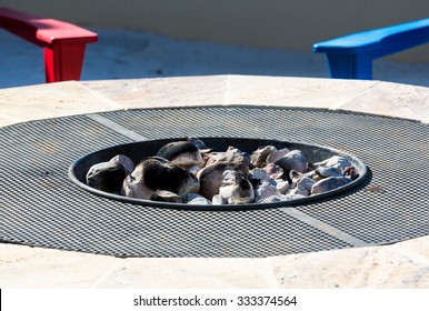 Gas Or Propane Powered Firepit With White Hot Coals And Rocks And Relaxing Chair