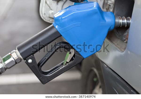 Gas pump\
nozzle in the fuel tank of a gyey\
car.