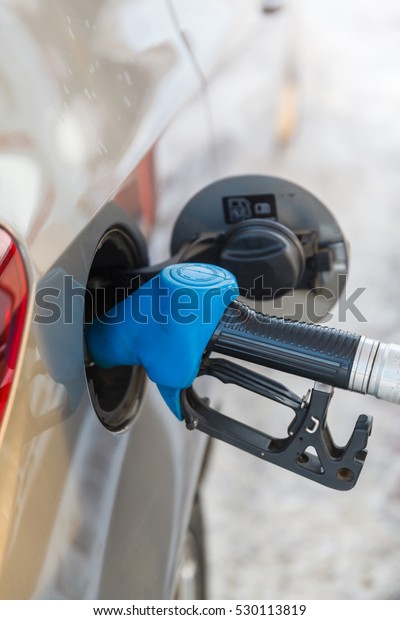 Gas pump\
nozzle in fuel tank of anew car,\
refuel