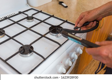 A Gas Safety Specialist Checks A Gas Stove In An Apartment Of A Residential Building For Leaks Of Household Gas Using A Measuring Device A Propane Analyzer