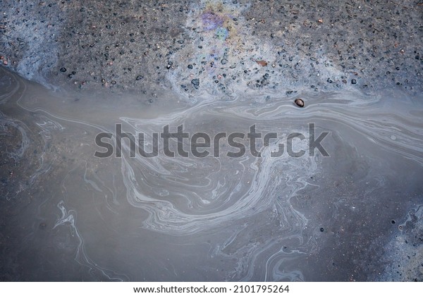 Gas stain on wet asphalt caused by a\
leak under a car or truck, abstract\
background