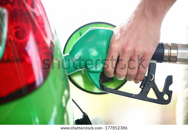Gas station pump. Man filling gasoline\
fuel in green car holding nozzle. Close\
up.