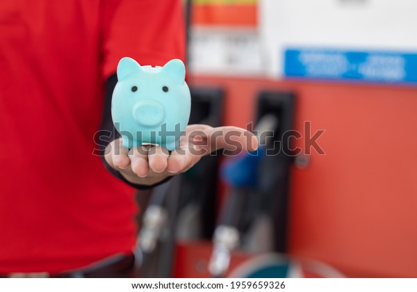 Gas station staff worker with piggy bank for\
save money from low fuel price, gas costs reduction, cut and saving\
gasoline drop price\
concept.