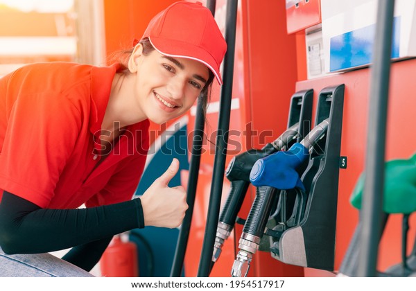 Gas station\
women worker staff Thumbs up at fuel nozzle dispensers happy\
service working refill cars\
gasoline
