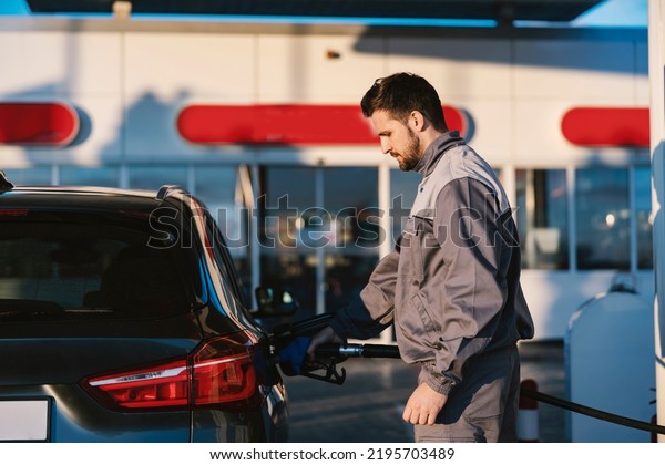 A gas station worker fills up the car tank at a\
gas station.