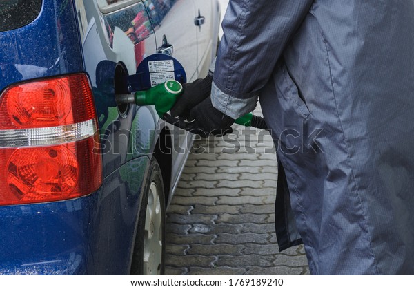 A gas station worker inserts a\
gas pistol into a car tank. Dolyna, Ukraine - May 12,\
2020.