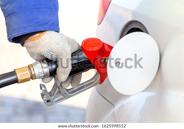 The gas station\
worker refuels the car.