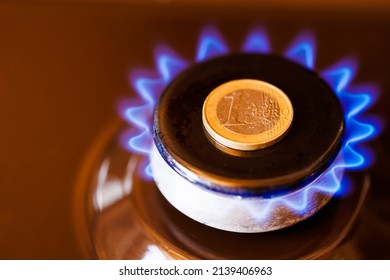 gas stove burner with one euro coin laid on top, burning natural gas with blue flame, gas price in European Union concept