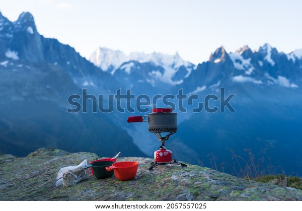 A gas stove with a pan of\
boiling water for a breakfast in the mountains near\
Chamonix.