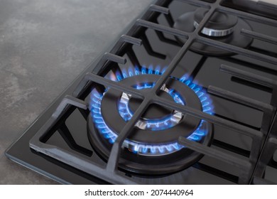 Gas Stove Top With Blue Flame On Dark Countertop Surface. Modern Kitchen Stove Cook