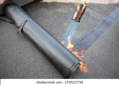 Gas torch heating up bitumen roofing felt