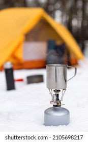 Gas tourist burner and pot, against the background of tent. Equipment for winter hiking, tourist cuisine.