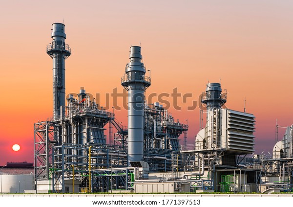 Gas turbine electric\
power plant industry in asian industrial estate isolated on sky of\
sunset and cargo ship background. Business gas turbine electricity\
generator. 