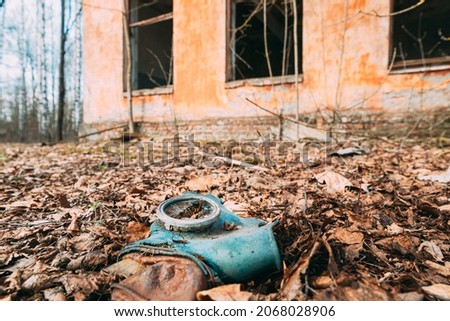 Gasmask Near Abandoned Ruined Old Village School Building In Chernobyl Resettlement Zone. Belarus. Chornobyl Catastrophe Disasters. Dilapidated House In Belarusian Village. Whole Villages Must Be