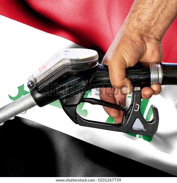 Gasoline consumption concept - Hand holding hose\
against flag of Iraq