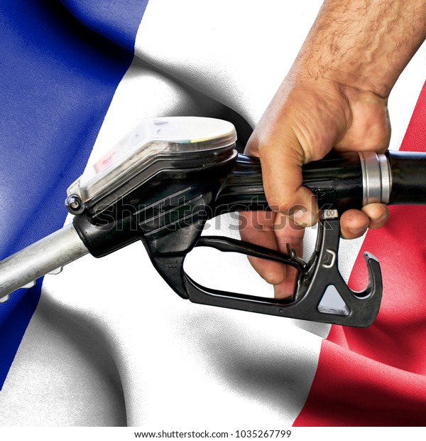 Gasoline consumption concept - Hand holding hose\
against flag of France