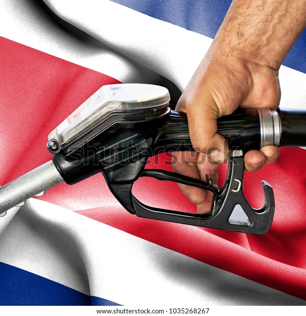 Gasoline consumption concept - Hand holding hose\
against flag of Costa\
Rica