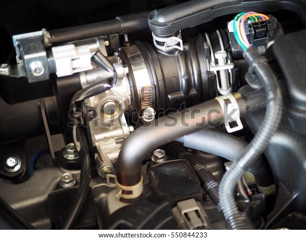 gasoline part engine closeup of a new small motor\
mini size eco-car selective focus on the throttle body with air\
intake, rubber pipes and electric sensor and controller plugs under\
engine hood