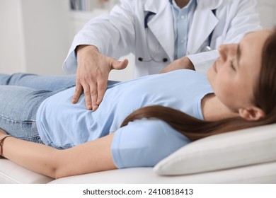 Gastroenterologist examining patient with stomach pain on couch in clinic, closeup - Powered by Shutterstock