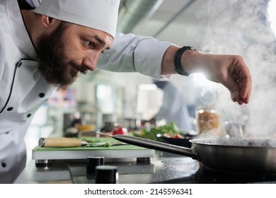 Gastronomic expert in professional kitchen seasoning gourmet dish served at fine dining restaurant. Master cook putting parmesan cheese in food while preparing meal for dinner service. - Powered by Shutterstock