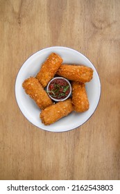 Gastronomy. Rustic presentation. Top view of fried mozzarella cheese fingers with a spicy dipping sauce, in a white bowl on the wooden table.