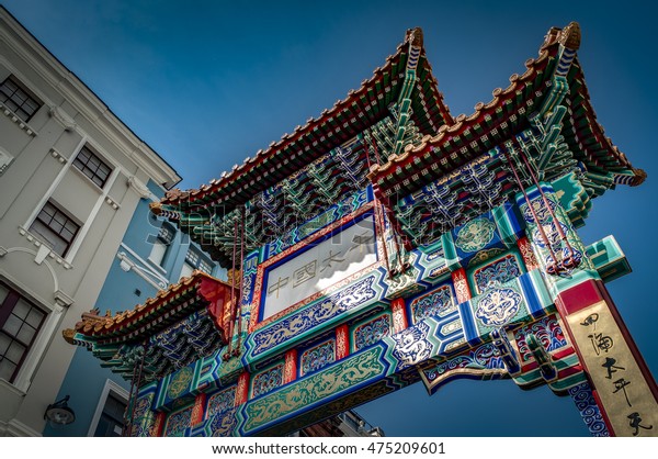 The Gate in chinatown, london, England with\
glazed yellow tiles, a golden dragon, painted panels, two white\
jade plaques and gold foil. The Chinese text translates \