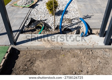 Gate foundation under construction with electrical wiring conduit and surrounding landscaping elements
