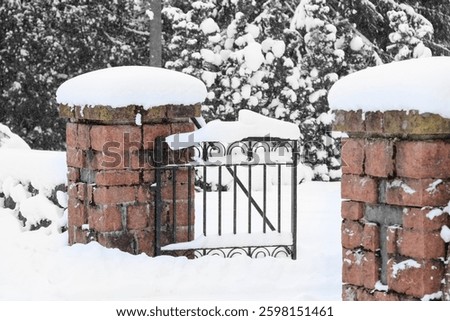 Gate to Kauniainen Cemetery. Snow covers the ground and it is snowing lightly. The background of the photo has been changed to black and white. Partially black and white. Empty space for text.