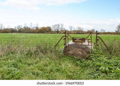 A Gate To A Village Cricket Pitch Is Blocked With A Hay Bale, Now Covered In Weeds.