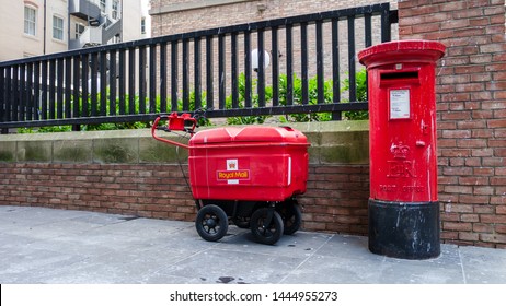 Gateshead, United Kingdom - July 8th 2019: Royal Mail/Post Office Red Pillar Post Box With Royal Mail Package Carrier Or Cart.