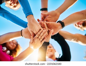 Gather around. Low angle shot of a group of young cheerful friends forming a huddle before a fitness exercise outside during the day. - Powered by Shutterstock