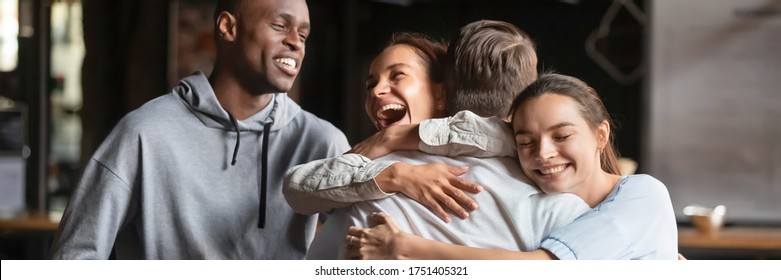 Gathered in cafe diverse friends meet guy mate cuddle him feel happy young people glad to see each other. Warm friendly relations, friendship concept. Horizontal photo banner for website header design - Powered by Shutterstock