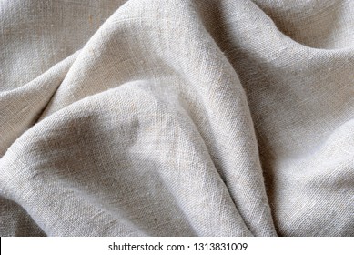 Gathered and folded texture of woven linen fabric with natural fibres in a close up full frame view