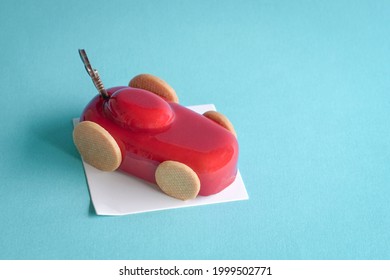 Gatou Cake In The Form And Shape Of A Red Sports Car. On Blue Background, Copy Space.