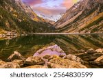 Gaube Lake, nestled in the Vallée de Cauterets in the French Pyrenees, offers serene reflections of snow-capped peaks surrounded by lush forests and rocky shores