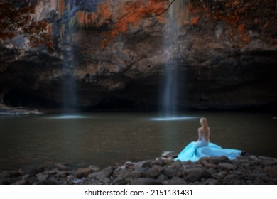 Gaussian Blur Image Of Young Woman Sitting Near Waterfall  